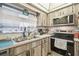 Galley kitchen with stainless steel appliances and light wood-look cabinets, illuminated by a window at 8438 Luray Dr, Port Richey, FL 34668