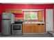 Simple kitchen with wood cabinets, stainless steel appliances, and red painted walls at 15806 Adobe Dr, Hudson, FL 34667