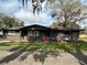 Ranch-style home with a red door, green trim, and a gravel driveway at 3234 Ella Ln, New Port Richey, FL 34655