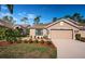 Tan house with two-car garage, landscaping, and walkway at 9609 Brookdale Dr, New Port Richey, FL 34655