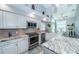 Kitchen boasts granite countertops, stainless steel appliances, and herringbone tile floor at 9609 Brookdale Dr, New Port Richey, FL 34655