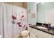Clean bathroom with granite vanity, floral shower curtain, and neutral tile flooring at 13455 Niti Dr, Hudson, FL 34669
