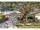 House exterior featuring a screened garage, mature landscaping, and a large oak tree at 14120 Whitecap Ave, Hudson, FL 34667