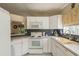 Bright kitchen with white cabinetry, tiled backsplash, stainless steel sink, and lots of counter space at 14120 Whitecap Ave, Hudson, FL 34667