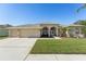 Single-story house featuring a three-car garage and well-manicured lawn at 7302 Melogold Cir, Land O Lakes, FL 34637
