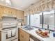 Kitchen features white appliances, light wood cabinets, and a window overlooking backyard at 12228 Magnolia Grove Ln, Hudson, FL 34667