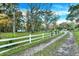 Gravel driveway with white fence and mature trees at 21000 Nina Ln, Brooksville, FL 34601
