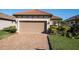 Tan house with tile roof, 2-car garage, and landscaped yard at 3312 Francoa Dr, Odessa, FL 33556