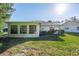 Back exterior view of the house with a large window and grassy yard at 2341 Masters Ct, Spring Hill, FL 34606