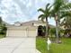 Tan two-story house with a three-car garage and palm trees in the front yard at 2902 Punta Palma Ct, Holiday, FL 34691