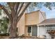 Tan siding townhome with green door, landscaping, and large tree at 4712 Stonepointe Pl, Tampa, FL 33634
