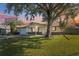 House exterior featuring a large tree, manicured lawn, and American flag at 6920 Medlar Dr, New Port Richey, FL 34653