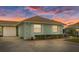 Evening view of a light green villa with brown roof, landscaping, and a carport at 8350 High Point Cir # 3, Port Richey, FL 34668