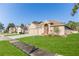 Houses on a tree-lined street showcasing a tan house with a two car garage at 13793 Dunwoody Dr, Spring Hill, FL 34609