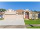 Tan house with brown roof, two-car garage, and landscaped yard at 13793 Dunwoody Dr, Spring Hill, FL 34609