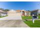 Tan house with brown roof, two-car garage, and landscaped yard at 13793 Dunwoody Dr, Spring Hill, FL 34609