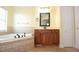 Elegant bathroom with corner jacuzzi tub, wood cabinets, and tiled flooring at 4634 Mapletree Loop, Wesley Chapel, FL 33544