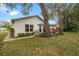 Backyard view of house with mature trees and landscaping at 6453 Wedgewood Dr, Spring Hill, FL 34606