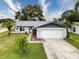 Cute Florida home with a gray roof, white garage door, and nicely landscaped yard at 8015 Pequena Dr, Port Richey, FL 34668