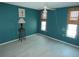 Teal bedroom with two windows and a decorative lamp at 13618 Stacey Dr, Hudson, FL 34667