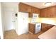 Kitchen has wood cabinets, white appliances, and access to another room at 7714 Jasmine Blvd, Port Richey, FL 34668