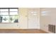 Living room with wood floors, a window, and white door at 7714 Jasmine Blvd, Port Richey, FL 34668