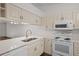 Updated kitchen featuring white appliances and cream cabinets at 1355 Powderpuff Dr # 908, Dunedin, FL 34698