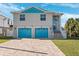 Two-story house with teal accents, two-car garage, and a paved driveway at 3215 Rose Arbor Dr, Hernando Beach, FL 34607