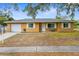 Tan house with gray roof, white garage door, and small front yard at 5121 Bromley Ave, Spring Hill, FL 34609