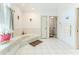 Spacious bathroom featuring a large soaking tub, white tile flooring, and view of a toilet room at 5286 Hamlet Cir, Spring Hill, FL 34606