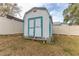 Exterior view of white shed with turquoise trim and double doors in partially fenced backyard at 5286 Hamlet Cir, Spring Hill, FL 34606
