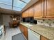 Eat-in kitchen with granite counters, wood cabinets, and a view to the living room at 8111 Merrimac Dr, Port Richey, FL 34668