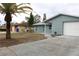 Newly renovated light blue house with a white garage door and landscaped yard at 8703 Robilina Rd, Port Richey, FL 34668