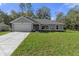 Newly constructed home with a gray exterior, two-car garage, and a well-manicured lawn at 12040 Pine Warbler Ave, Brooksville, FL 34614