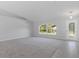 Bright and airy living room with a large window and gray carpeting. Access to other areas of the house at 12040 Pine Warbler Ave, Brooksville, FL 34614
