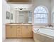 Bathroom with double vanity, large soaking tub, and an arched window at 12312 Millington Ave, Weeki Wachee, FL 34614