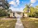 Cute yellow house with palm trees, landscaped yard, and walkway at 2013 Gulfview Dr, Holiday, FL 34691