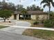 Tan house with brown roof, landscaping, and a curved driveway at 3039 Sandpiper Ct, Clearwater, FL 33762