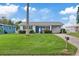 Cute bungalow style home with a grassy yard, palm tree, and blue door at 4424 Floramar Ter, New Port Richey, FL 34652