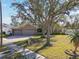House exterior features a large front yard, double garage, and mature tree at 609 Salt Lake Dr, Tarpon Springs, FL 34689