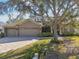 Beautiful home exterior with a three-car garage and lush landscaping at 609 Salt Lake Dr, Tarpon Springs, FL 34689