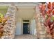 Front door entrance with stone columns and red plants at 8424 Bluevine Sky Dr, Land O Lakes, FL 34637