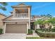 Two-story house with a balcony, two-car garage, and palm trees at 9323 Bella Vita Cir, Land O Lakes, FL 34637