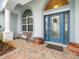 Brick porch with a blue door, potted plants, and a wooden bench at 13721 Mill Pl, Odessa, FL 33556