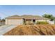 Tan one-story house with gray roof, attached garage, and landscaped yard at 4372 Odin St, Spring Hill, FL 34608