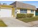 Cute yellow house with a white garage door and well-manicured lawn at 7037 Versailles N # 15, Pinellas Park, FL 33781