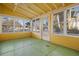 Charming enclosed sunroom with yellow walls and a green floor at 106 Banana St, Tarpon Springs, FL 34689