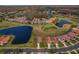 Panoramic aerial shot of a charming community boasting well-manicured grounds, a lake, and verdant golf course views at 1082 Dartford Dr, Tarpon Springs, FL 34688