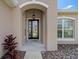 Front entry with arched doorway, black door, and mature landscaping at 14639 Balloch Dr, Hudson, FL 34667