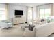 Bright living room with light beige couches, an ottoman, and a large TV at 2473 White Ladyfish Rd, Wimauma, FL 33598